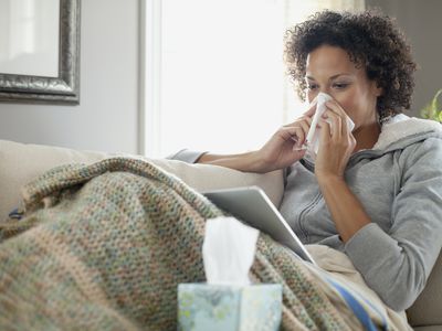 Woman with a cold looking at digital tablet