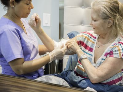 Home healthcare nurse tending to picc line of recovering patient