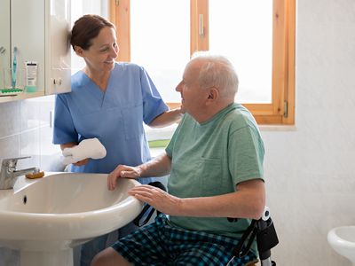 Nurse helping man wash up at a sink