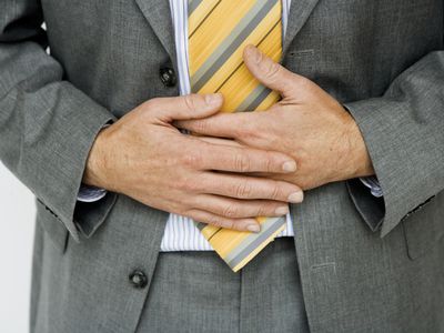 Man in suit and tie holding stomach