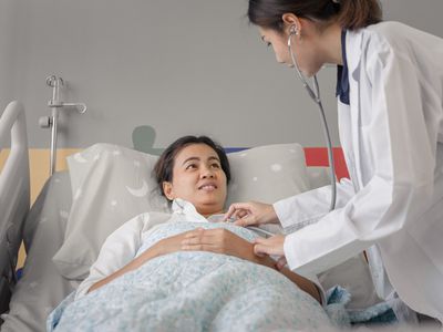 Physician assistant checks patient in hospital bed