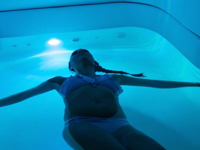 Woman wearing a bathing suit while floating in a sensory deprivation tank. 