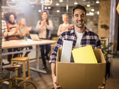 Man leaving an office with his belongings in a cardboard box