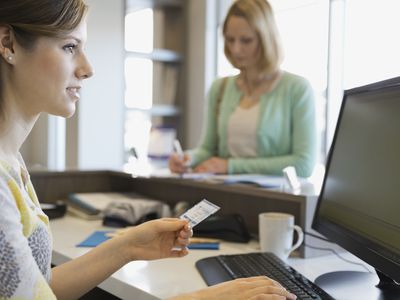 A receptionist examines a patient’s insurance information.