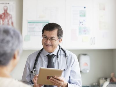 Hispanic doctor with digital tablet talking to patient