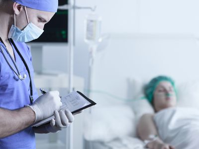 patient resting after surgery with doctor writing on a chart