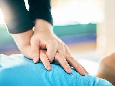 Close up of White hands on an unseen person's chest giving CPR