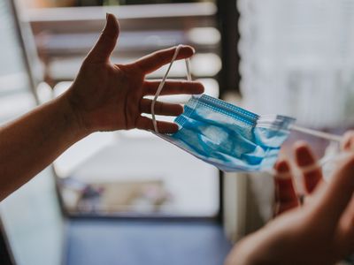 A person holding a surgical mask to protect from transmitting COVID-19