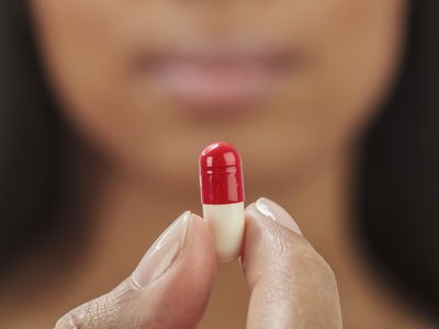 woman holding red and white pill capsule