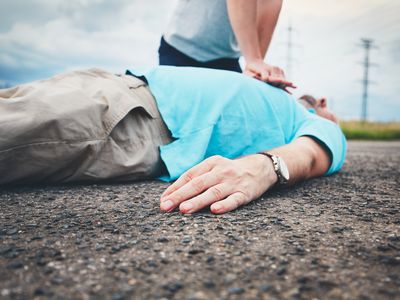 Midsection Of Man Resuscitating Friend Lying On Road