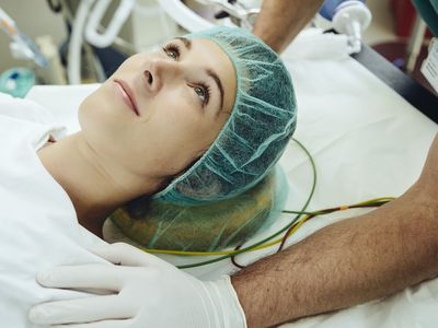 Operating nurse soothing patient on table in operating room