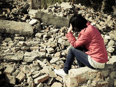 Person sits amid rubble