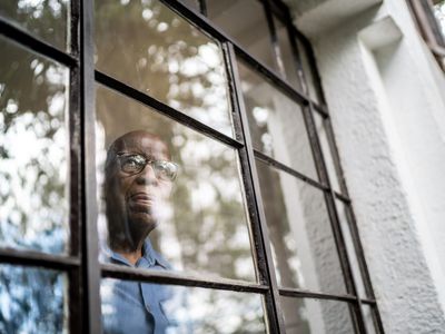 Sad older man looking out a window