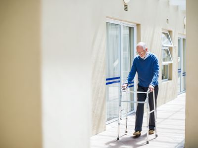 Senior man using walker on sidewalk