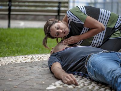 A young person is checking for breathing for a person who is unconscious and may be in shock