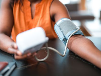 Close up on hands of a mid adult female using a medical device in a domestic dining room.