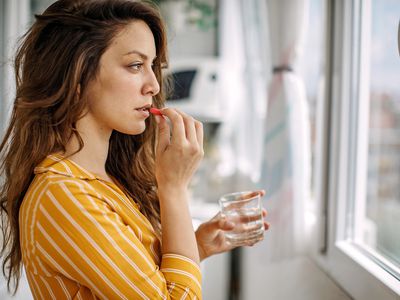 Young adult taking a supplement pill at home