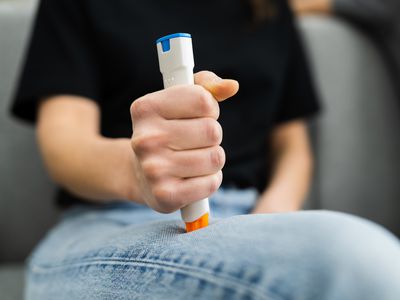 Person demonstrating injecting an auto epinephrine pen injector into leg