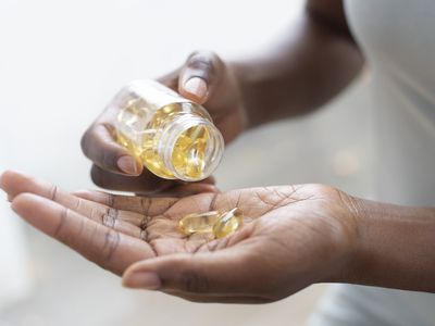 Woman pouring vitamin D capsules into her hand