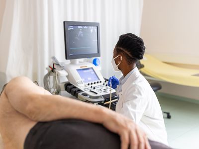 Heart specialist doctor looking at a computer screen while doing an echocardiogram test of a senior patient in the clinic. Doctor doing heart ultrasound test of patient in cardiology hospital.