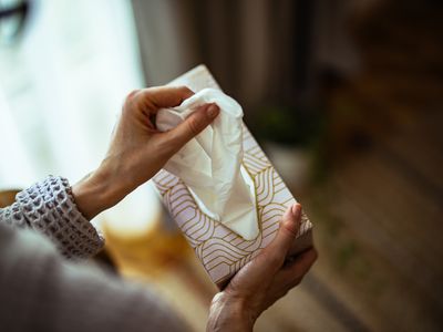 From above photo of woman hand pulling handkerchief from the tissue box at home.