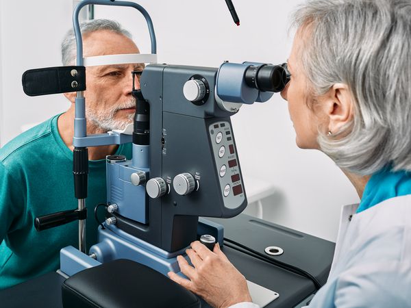 An optometrist examining a mature patient's eye.