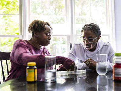 Two women taking vitamins together in their kitchen