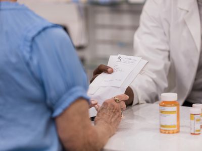 Pharmacy tech handing customer a prescription