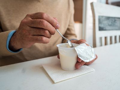 A person eating yogurt out of a plastic container. 