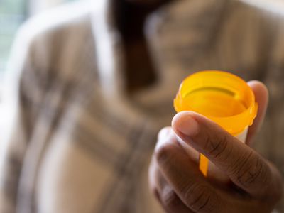 Close up of person's hand holding open pescription pill bottle