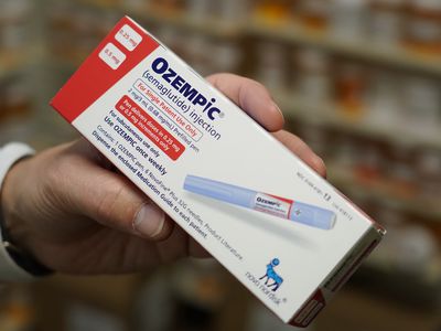 Close-up of pharmacist's hand holding a box of Ozempic (semaglutide) at a pharmacy