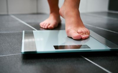 A close up of a woman's feet with one stepping on a scale