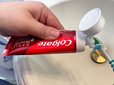 A person applying the Colgate Optic White toothpaste on a toothbrush