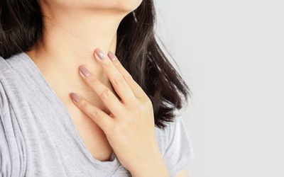 woman hand self checking thyroid gland on her neck