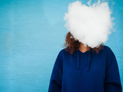 Young woman with her head in a cloud of vapor smoke